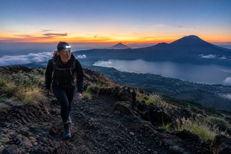 Hiker walking uphill on Mount Batur volcanic trail before sunrise