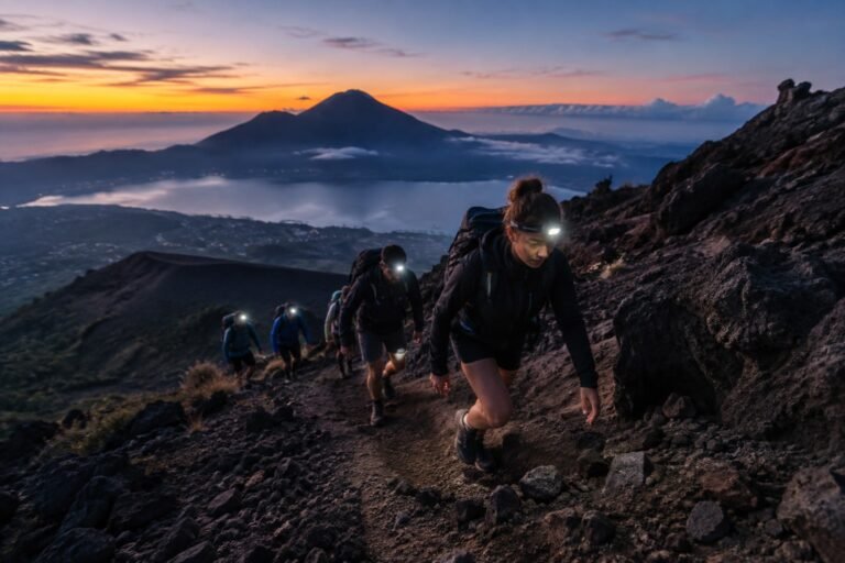 Hikers climbing a steep volcanic section of Mount Batur before sunrise