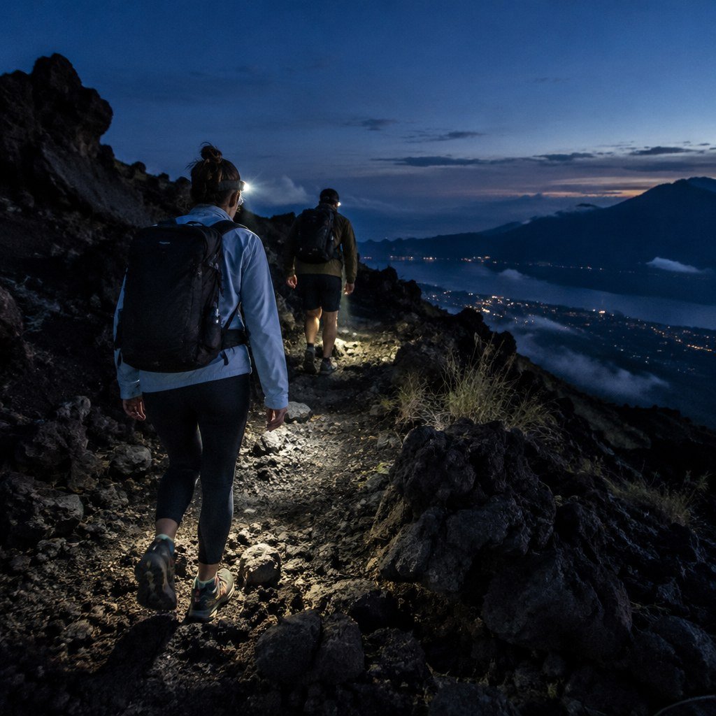 Trekking group walking up Mount Batur's rocky volcanic trail before sunrise